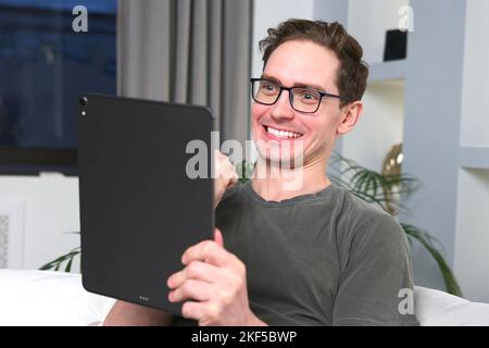 A young happy and excited Caucasian man showing a winning gesture while looking at his tablet Stock Photo