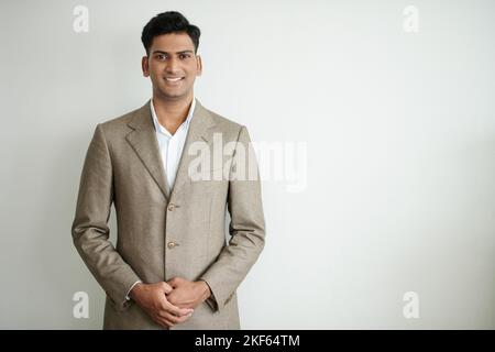 Portrait of smiling Indian businessman standing against white wall Stock Photo