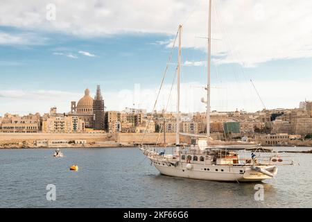 Valletta, Malta - November 11, 2022: Panoramic view of the capital city from Sliema, with a sailing boat, on a sunny cloudy day Stock Photo