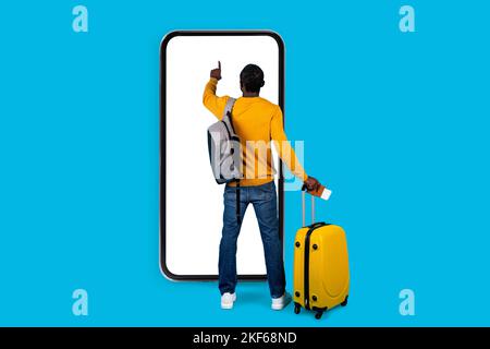 African american man traveller standing by huge smatphone, touching screen Stock Photo