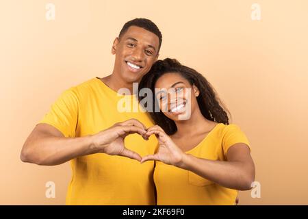 Loving african american couple cuddling and making together heart shape gesture with their hands as a sign of their love Stock Photo