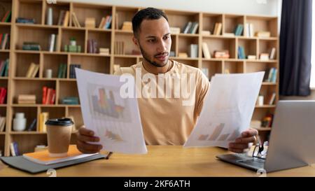 Arab male freelancer man working with documents and laptop at home office, checking financial papers, panorama Stock Photo