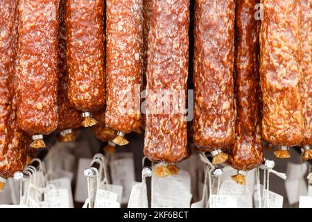 Salami jerky sausages hanging in fridge in supermarket. Stock Photo