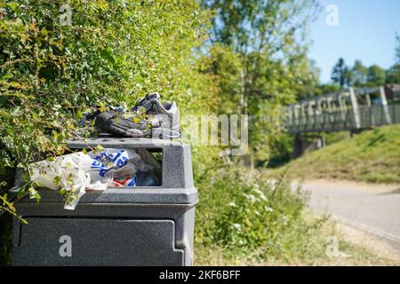 Countryside village eyesore! Close up of very full, overflowing council rubbish bin alongside road in pretty Worcestershire village in need of emptying. Stock Photo