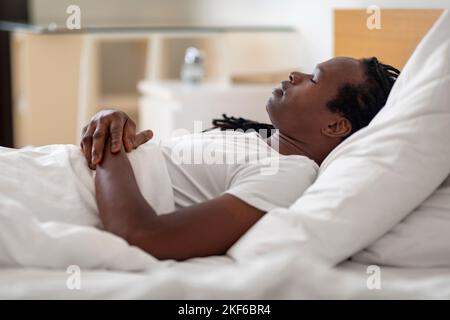 Side View Of Young Black Male Sleeping In Bed At Home Stock Photo