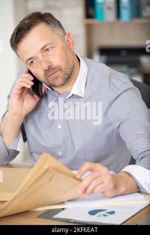 serious architect sat at desk looking through envelopes Stock Photo