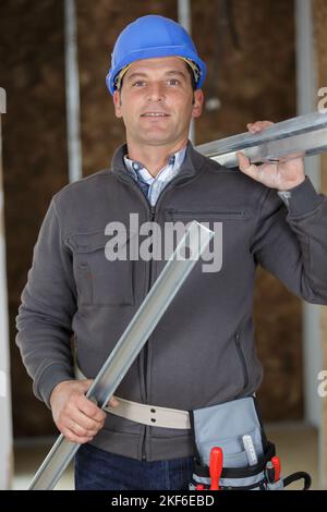 smiling construction worker carrying a metal bars Stock Photo