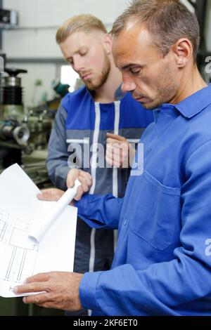 men in factory looking at paperwork Stock Photo