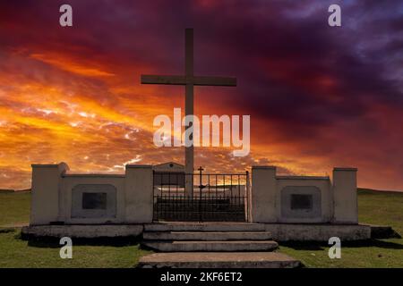 Millenium Cross on the hilltop against colorful clouds of the setting sun.Clonmel, Ireland. Stock Photo