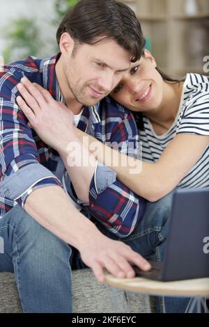 happy man and woman relax on couch hugging watching laptop Stock Photo