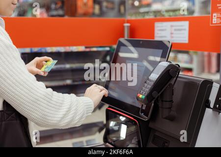 ?ustomer woman buys and pays at checkout of self-service vending machine in a modern supermarket Stock Photo