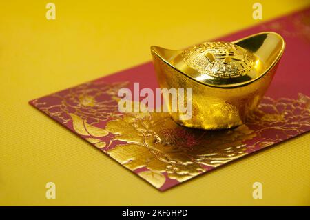 Chinese New Year packets with Chinese Gold Ingots on yellow background. Stock Photo