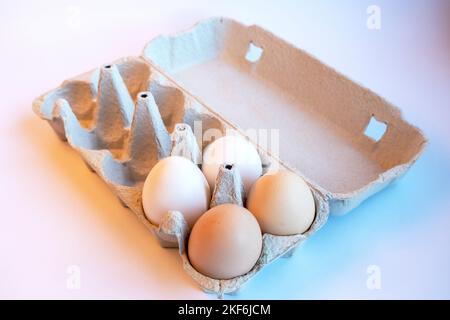 Fresh two light brown and two white eggs in a paper box and six empty spaces for healthy food. Egg container made of recyclable material. Stock Photo