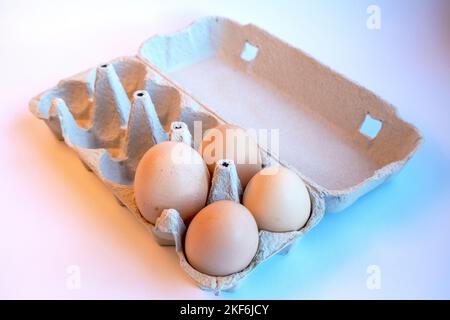 Four fresh light brown eggs in a paper box and six empty spaces for healthy food. Egg container made of recyclable material Stock Photo