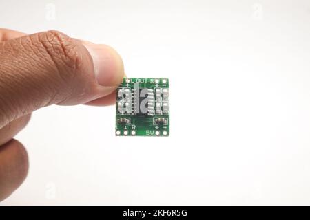 A small audio amplifier module held in one hand is used as DIY material for the electronics hobbyist. Stock Photo