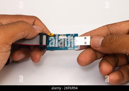 An AVR microcontroller USB downloader held in two hands. Stock Photo