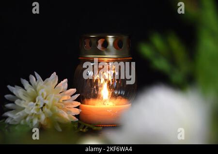 Sympathy card with candle and white chrysanthemum on dark background Stock Photo