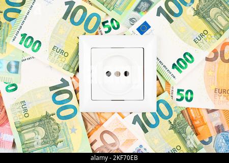 White socket over many Euro banknotes as background. Concept of increasing prices for electricity in Europe. High energy cost, world and Europe's ener Stock Photo