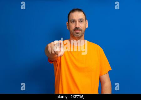 Portrait of a smiling bearded man pointing fingers at camera isolated over blue background Stock Photo