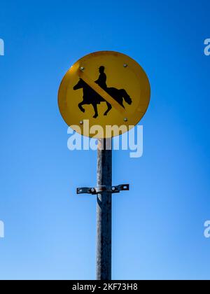 Close-up of a no horse riding signpost on a blue sky background. Stock Photo