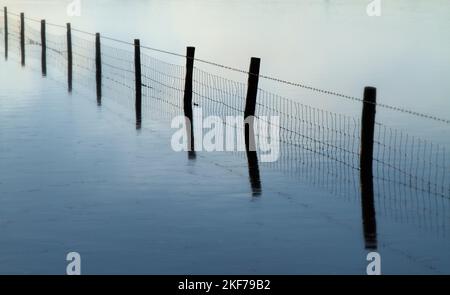 Reflection Of A Wire Fence In Calm Water On A Calm Misty Morning, Keyhaven UK Stock Photo