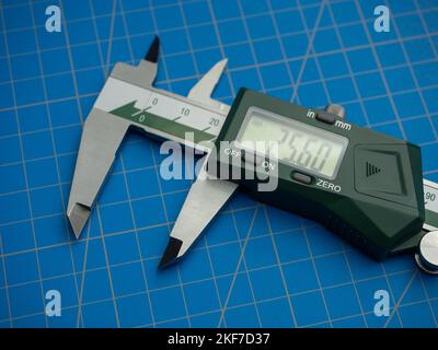 Photo of a digital vernier caliper with centimeters and millimeters on a blue background cutting mat Stock Photo