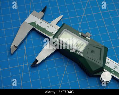 Photo of a digital vernier caliper with centimeters and millimeters on a blue background cutting mat Stock Photo