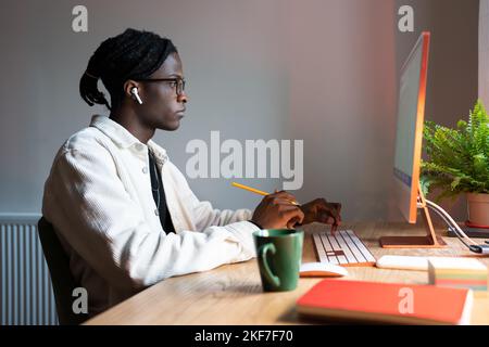 Progressive focused African American man designer working sits at office desk with computer Stock Photo