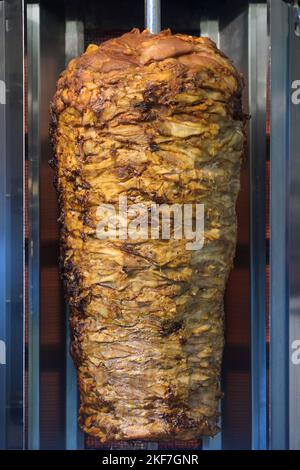 Vertical rotisserie grill with layered meat for kebab or gyros, fast food on the street,selected focus Stock Photo