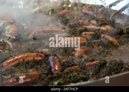 Large pot with steaming curly green kale and sausages at an autumn market, German street food in the cold season, selected focus, narrow depth of fiel Stock Photo