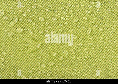 Waterproof clothing or upholstered furniture made from waterproof textiles. Drops of water on green textiles with water-repellent properties. Stock Photo