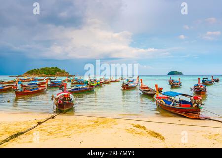 Small harbor with long tail boats at Ko Lipe island, Thailand, shortly before tropical storm. Big and heavy dark clouds above sea. Detail of wooden bo Stock Photo