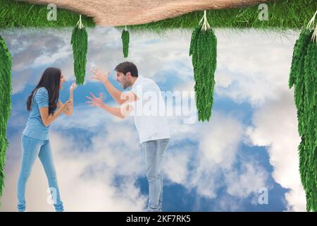 Caucasian couple arguing against upside down trees and and blue sky with copy space Stock Photo