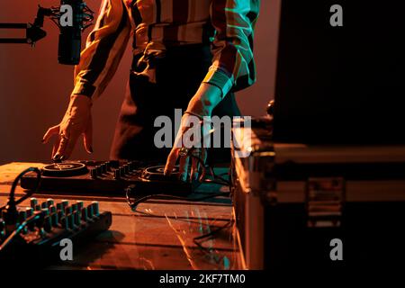 Woman artist using mixing turntables to play music at party, having fun with audio dj equipment for techno performance. Playing stereo sounds with electronics, microphone and headphones. Stock Photo