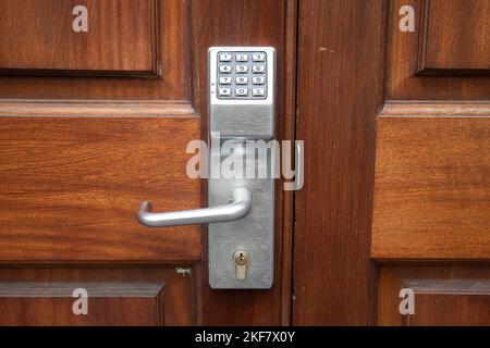 Digital door lock with metal handle on a wooden door. Door password safety system, code keypad closeup. Stock Photo