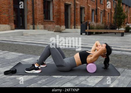 Fitness woman doing abs exercise with massaging roller outdoor Stock Photo