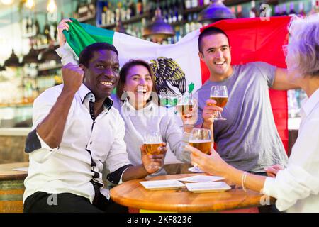 Joyful fans of the Mexican team celebrating the victory in night bar Stock Photo