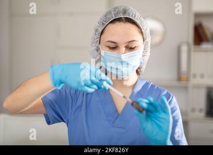 Nurse fills syringe with injection solution Stock Photo