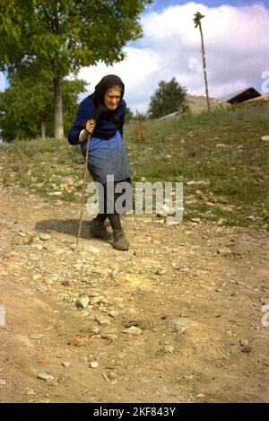 Ilfov County, Romania, approx. 2000. Elderly woman walking down a rocky path with the help of a stick. Stock Photo