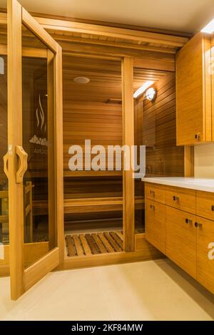 Sauna room in basement bathroom with bamboo wood vanity and white marble floor inside luxurious stained cedar and timber wood home. Stock Photo