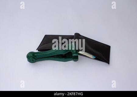 Image of a clamp that keeps a wallet closed and blocked from which banknotes come out. Reference to the global crisis, rising prices and savings Stock Photo