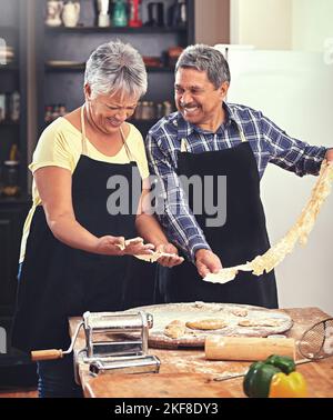 Homemade pasta is on the menu. a mature couple cooking together at home. Stock Photo