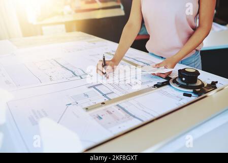 Architecture is an art form. an unrecognizable architect working on her drafting table. Stock Photo