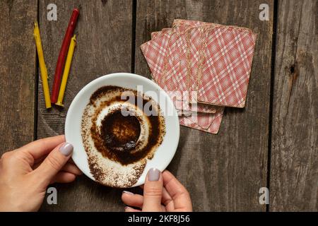 coffee grounds in the hands of a fortune teller and cards and candles on the table, fortune telling and prediction, fortune telling from coffee ground Stock Photo