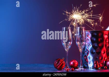 Glasses with Christmas sparkler, bucket and balls on dark background Stock Photo