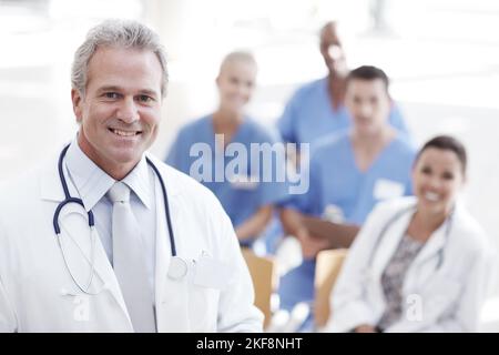 Hes a leader in healthcare. A doctor standing with colleagues in the background. Stock Photo