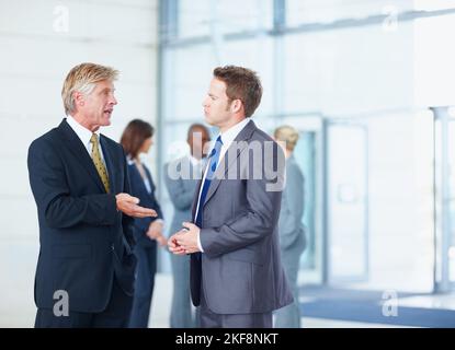 Executives discussing with business people. Portrait of male executives discussing with business people in background. Stock Photo