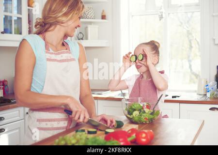 Hey mom, look at me. Cute little girl playfully holding cucumber slices over her eyes. Stock Photo