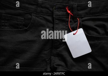 womens denim shorts with white blank paper price tag for text on table, price tag on shorts, place for price Stock Photo
