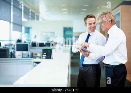 Executives using touchpad PC. Two business men discussing while using tablet PC. Stock Photo